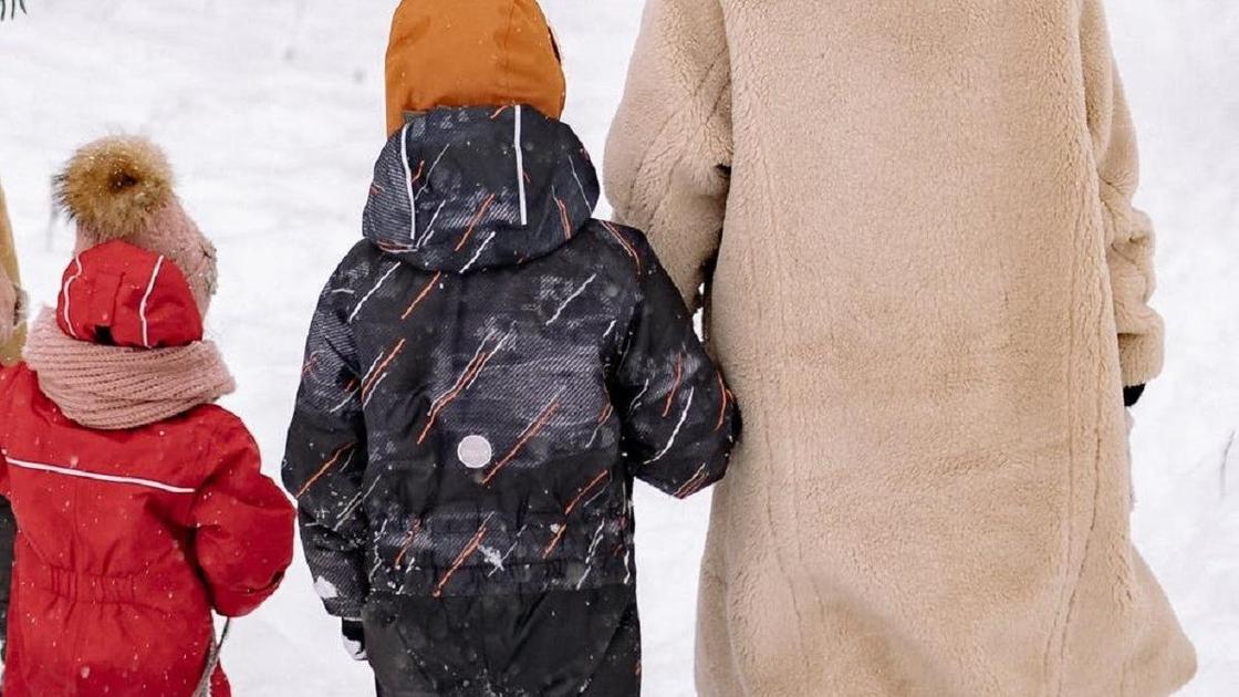 Балаларын жетектеп бара жатқан әйел