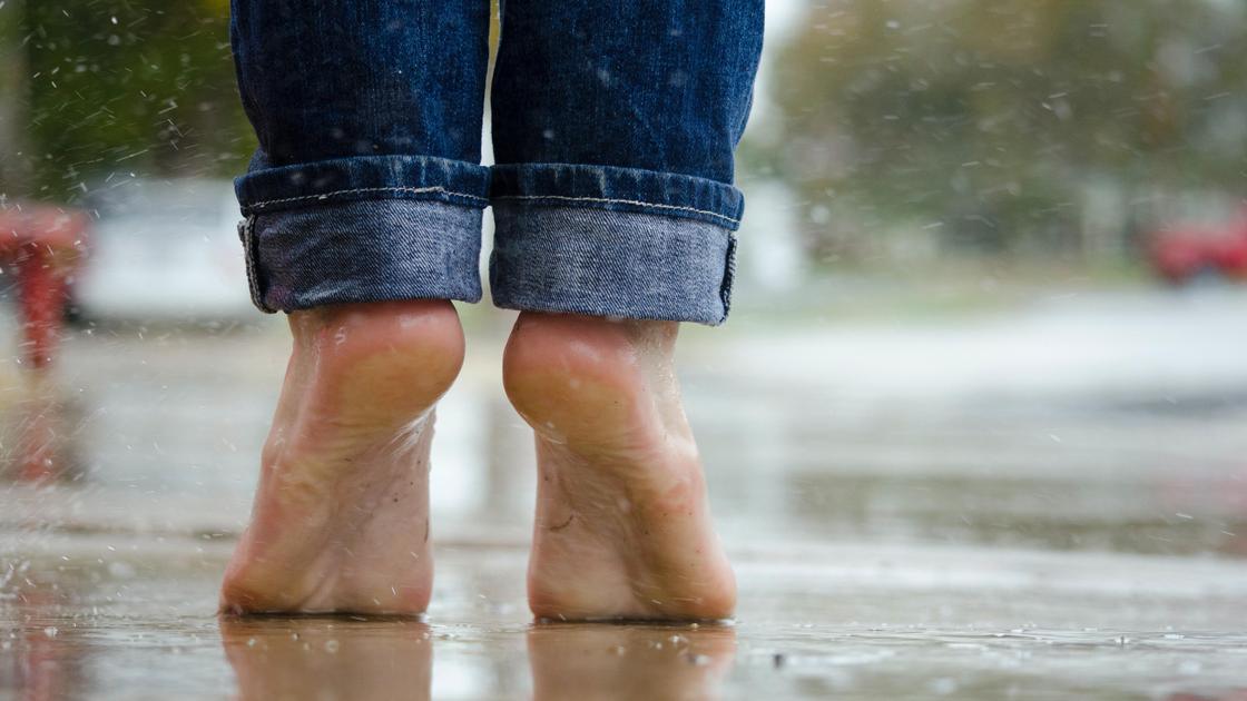 Человек в джинсах стоит под дождем