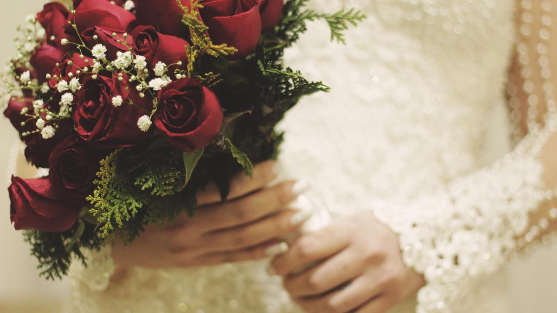 Невеста держит в руках букет красных  роз