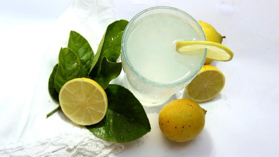 Стакан лимонада в окружении лимонов