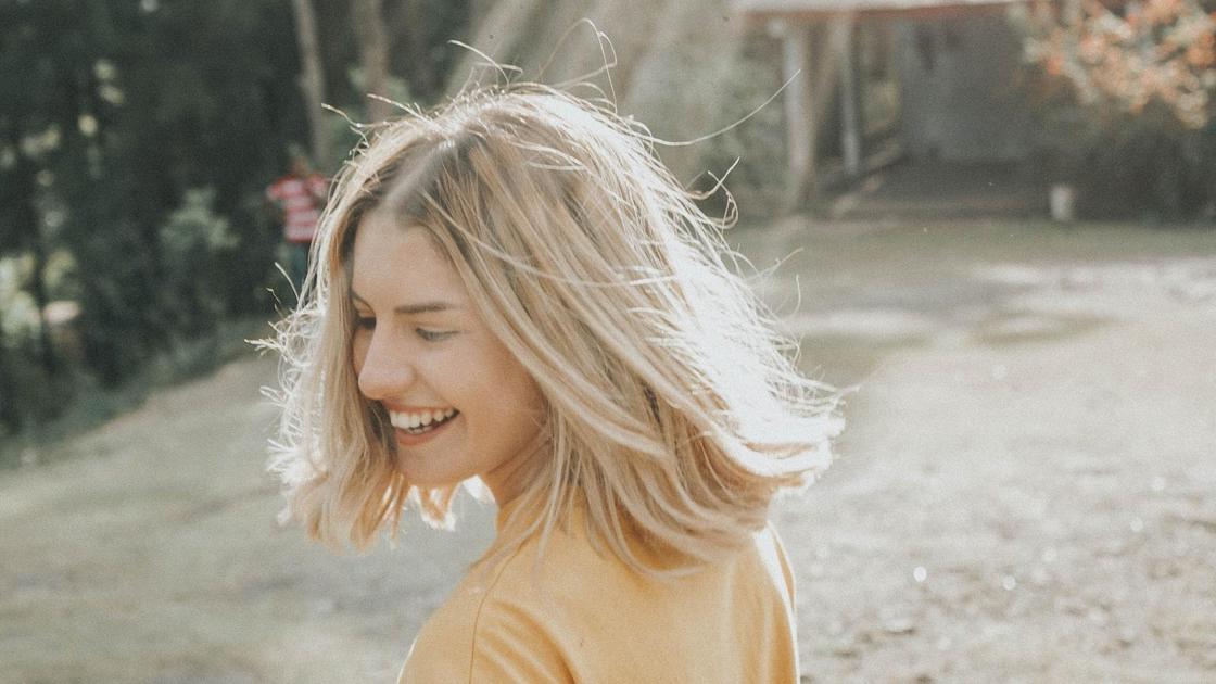 Девушка смеется в лучах солнца