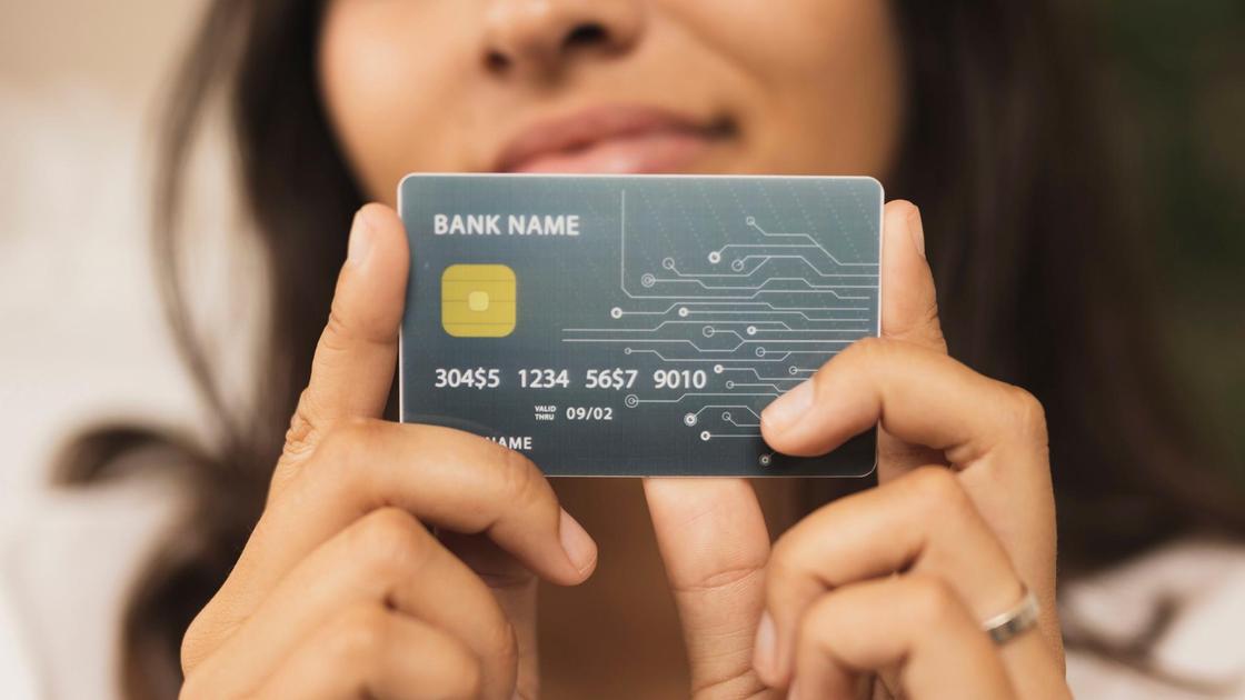 Девушка держит перед собой банковскую карту с дефолтной информацией