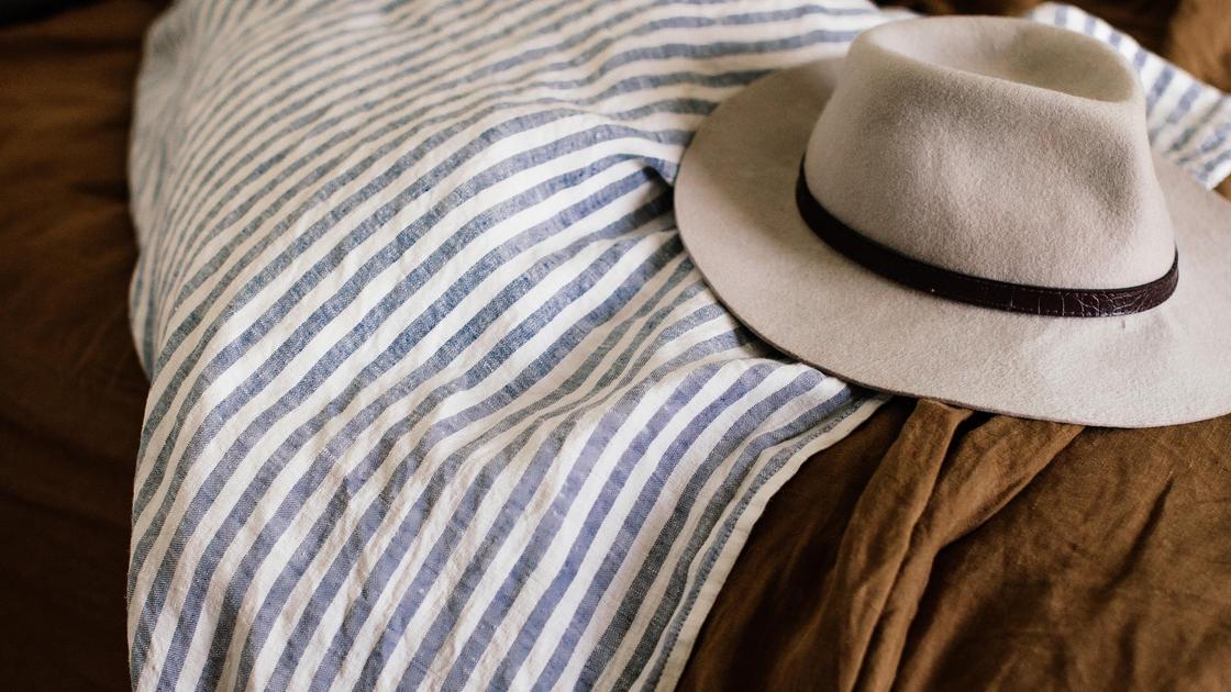 Шляпа лежит на кровати с одеялом