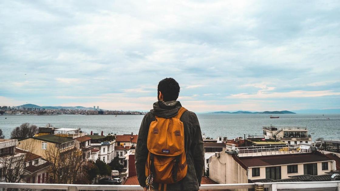 Мужчина с рюкзаком на фоне города и моря