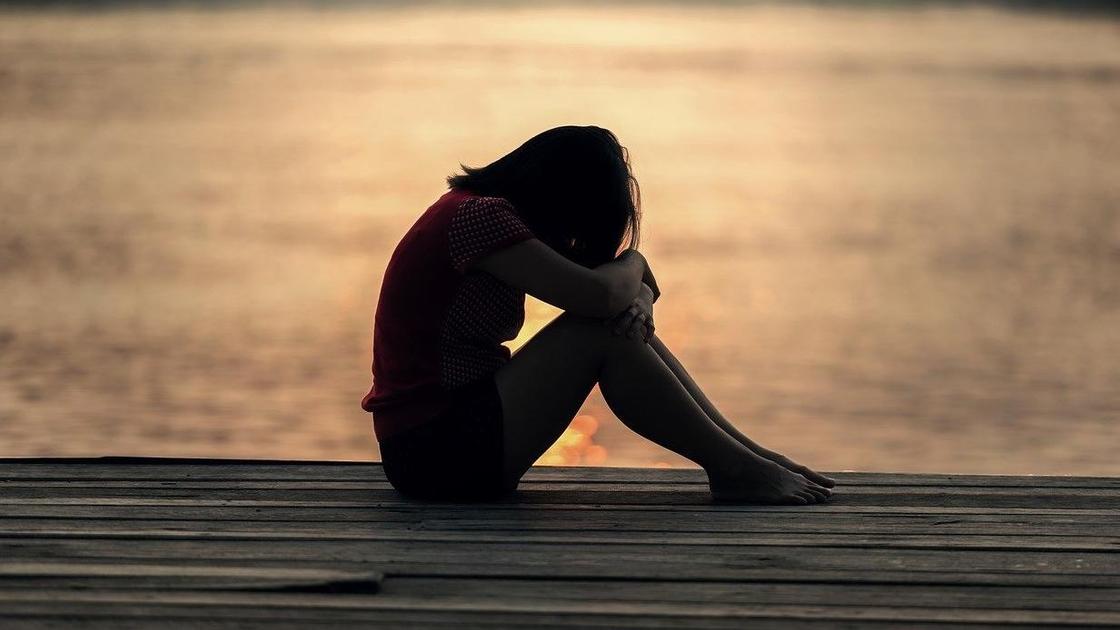 Девочка сидит, обняв колени