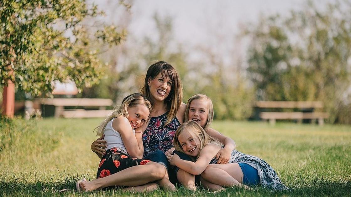 Мама сидит на газоне с тремя дочерьми