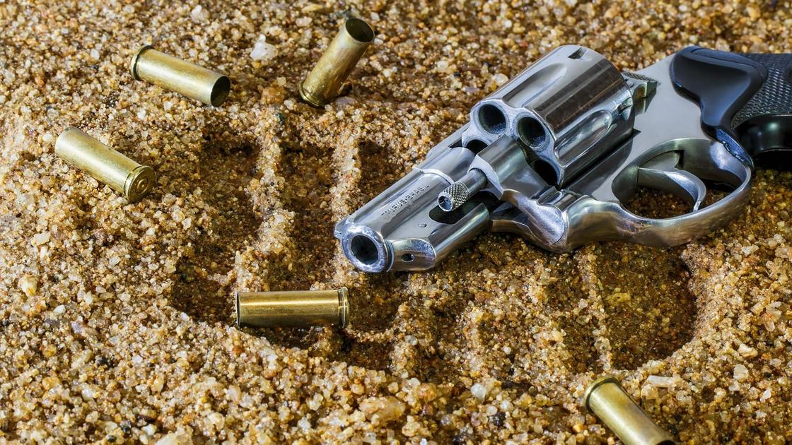 Огнестрельное оружие и патроны лежат на песке
