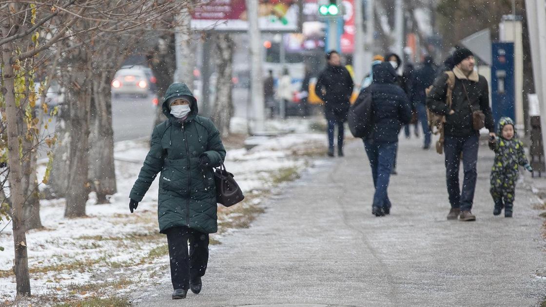 Женщина в маске идет по зимнему городу