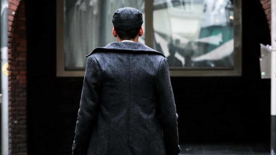 Мужчина в пальто стоит на улице