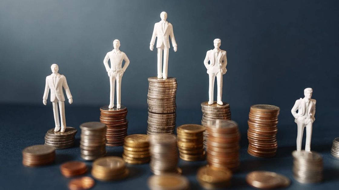 Фигурки людей стоят на столбиках монет