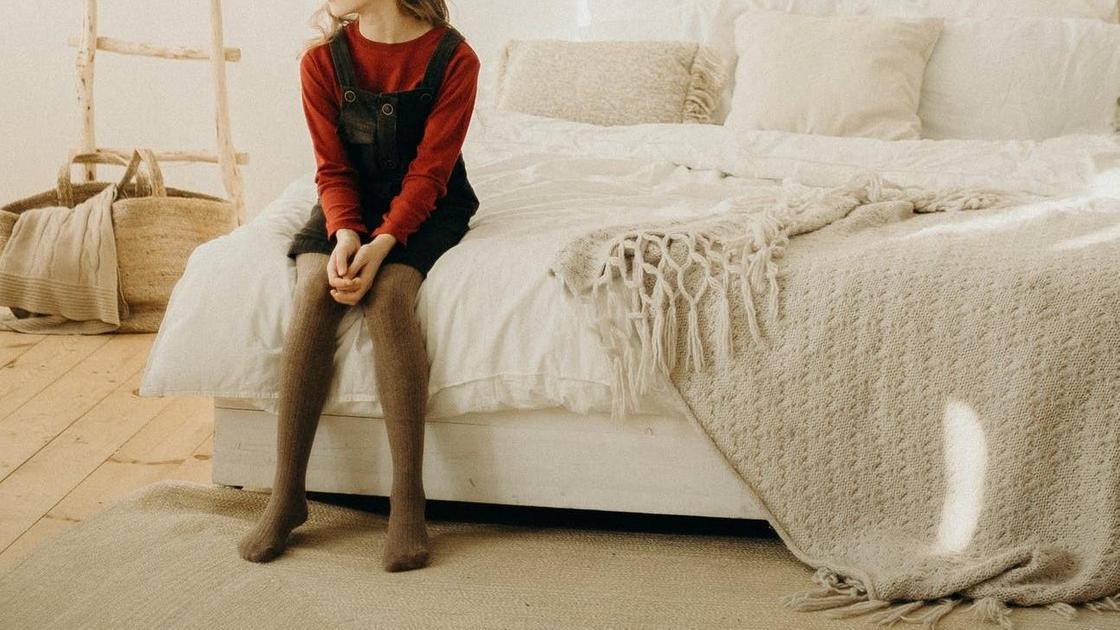Девочка сидит на кровати дома