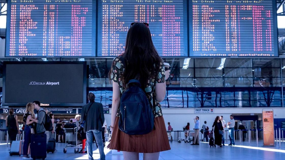 Девушка смотрит вверх на таблицы с расписанием рейсов