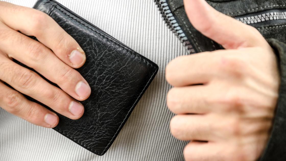 Мужчина кладет кошелек во внутренний карман одежды