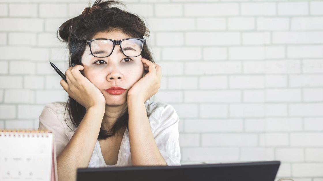 Уставшая женщина в очках сидит за компьютером