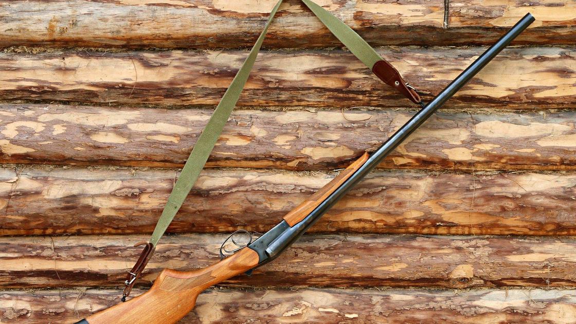 Ружье висит на стене на крючке