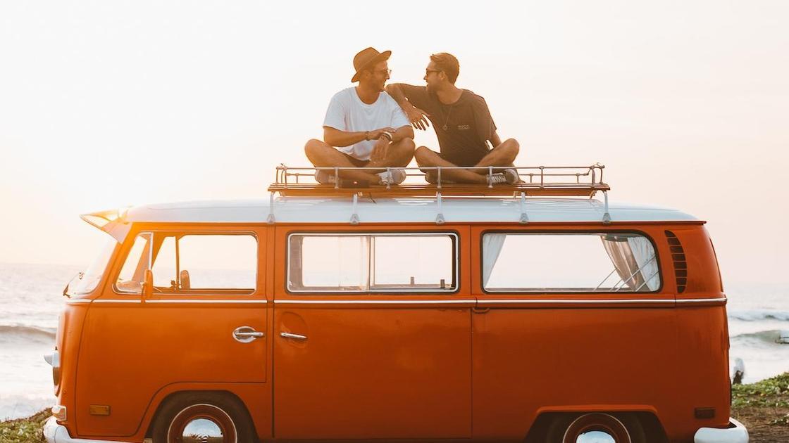Двое мужчин сидят на крыше красного микроавтобуса
