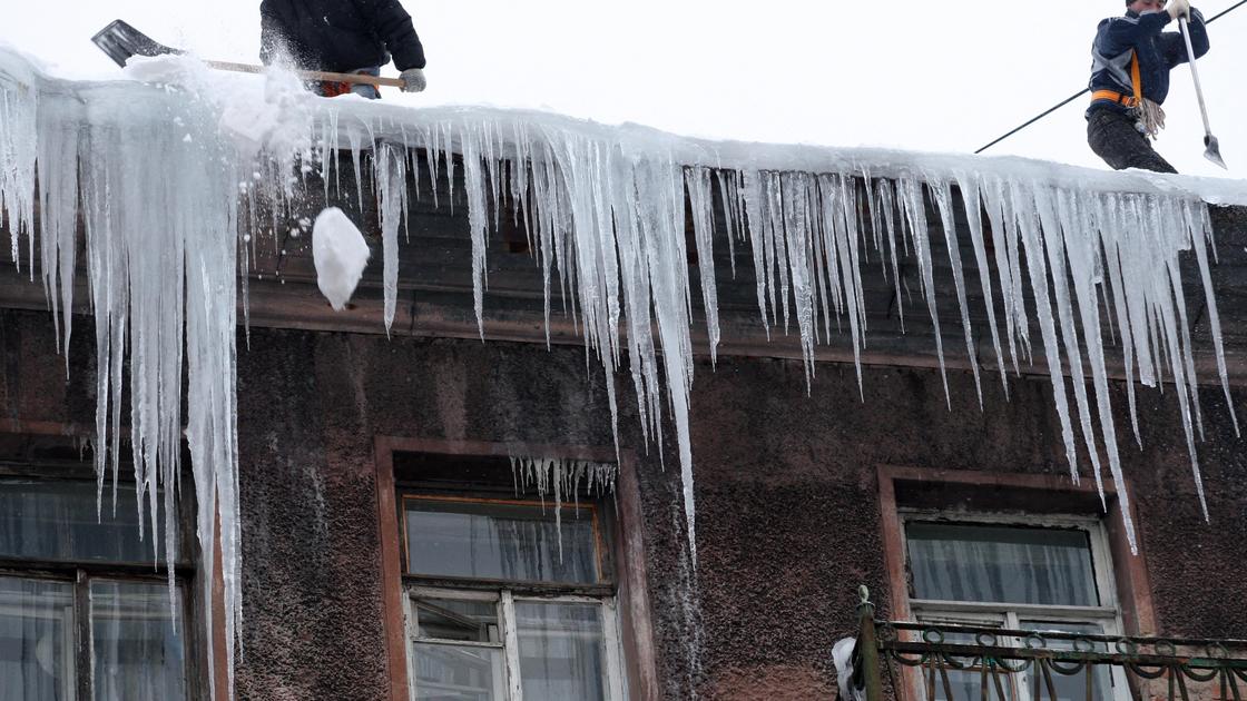 Рабочие сбивают лед с крыши