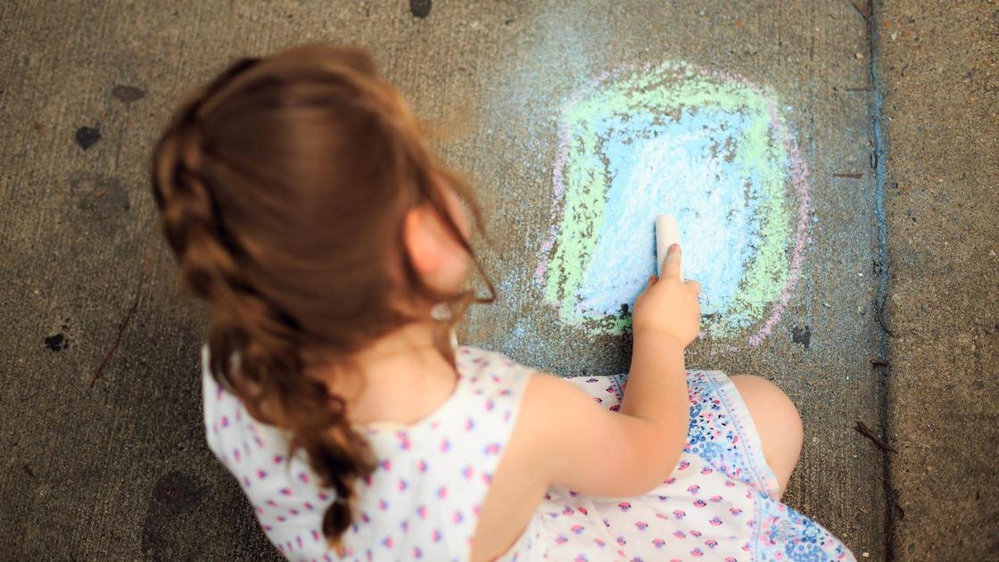 Девочка рисует мелом на асфальте