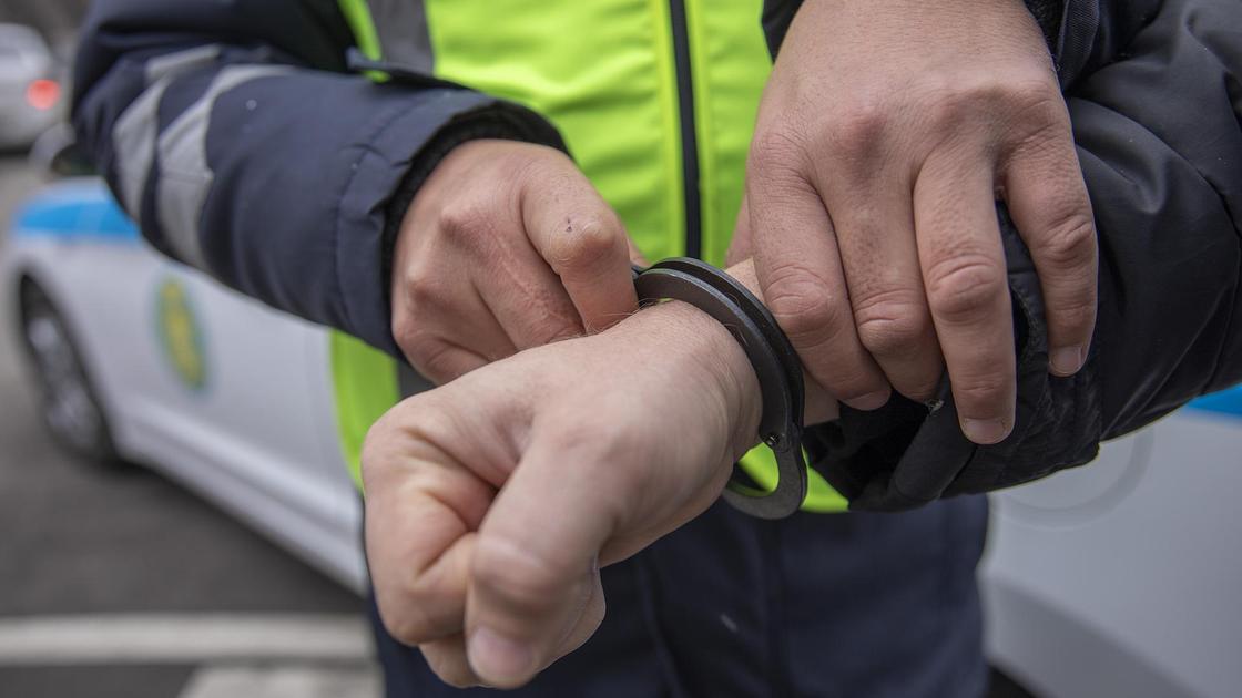 полицейский надевает наручники на задержанного
