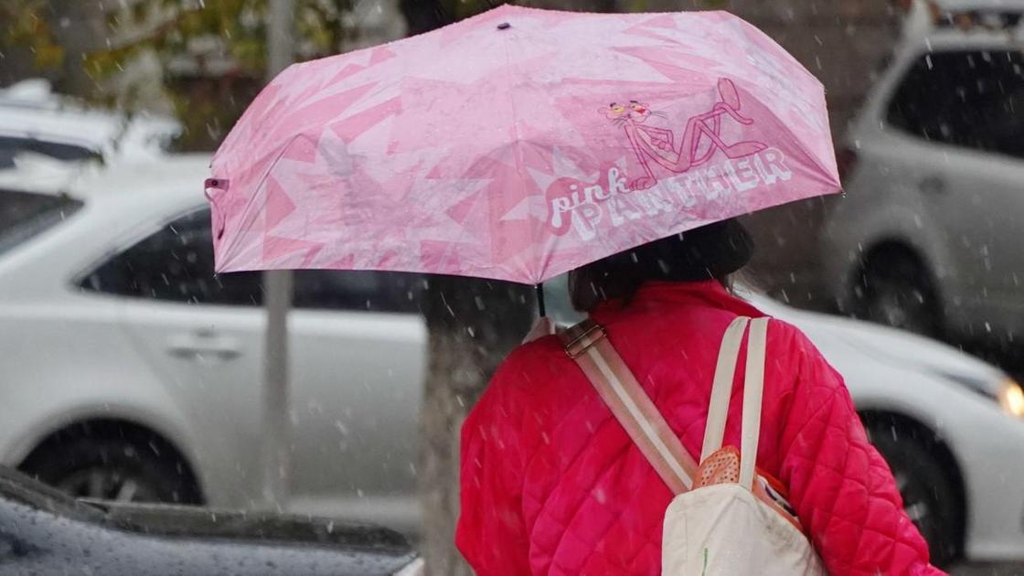 Женщина идет по улице под зонтом