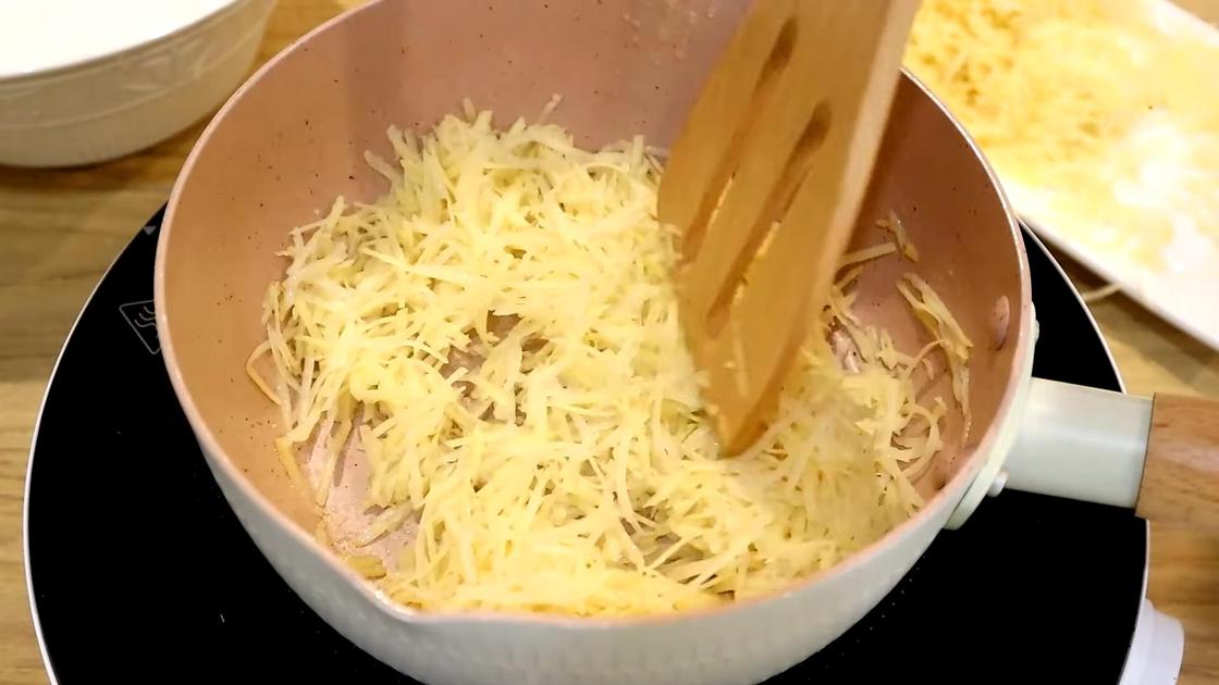 На сковороде деревянной лопаткой перемешивают тертый картофель