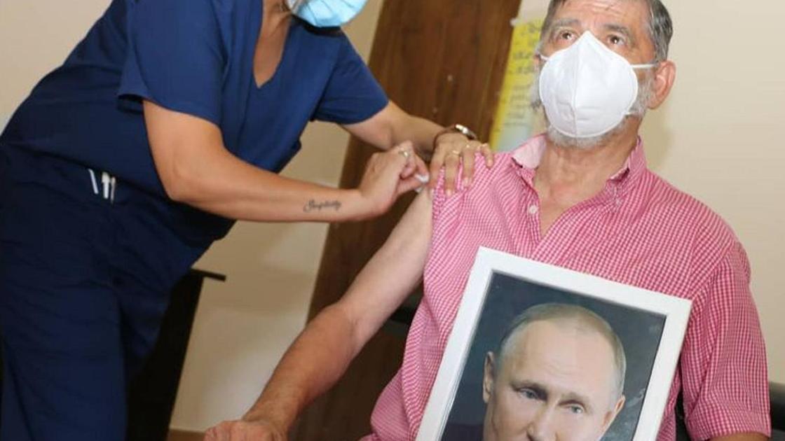 Хуан Карлос "Чинчу" Гаспарини с фотографией Путина получает вакцину