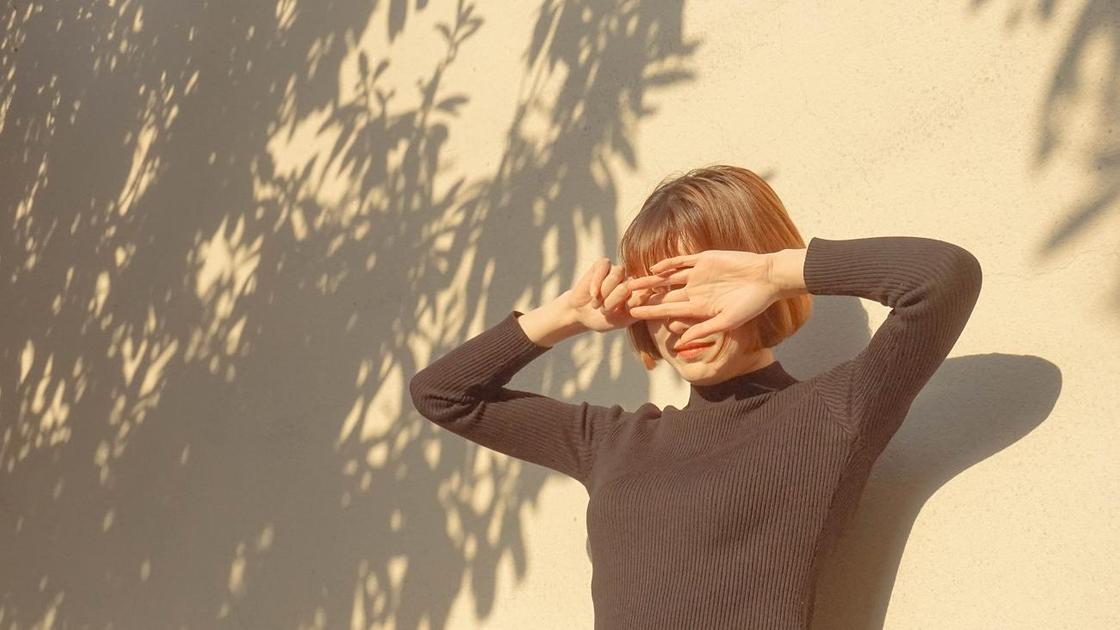 Девушка прикрывает лицо руками от солнца
