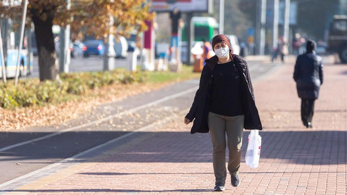 Женщина в маске идет по улице