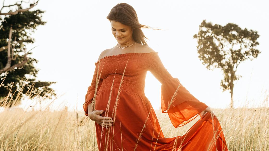 Беременная женщина гуляет в поле