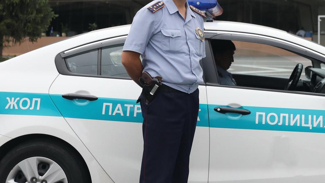 Полицейский стоит у служебного авто