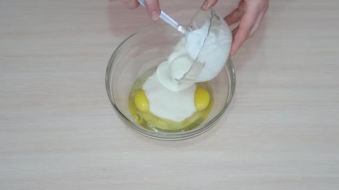 В миску с разбитыми куриными яйцами добавляют сметану