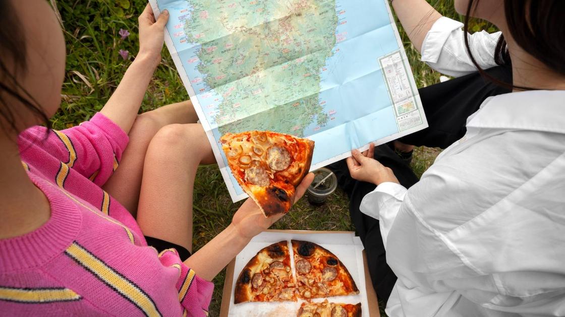 Молодые люди держат в руках карту и кусочек пиццы