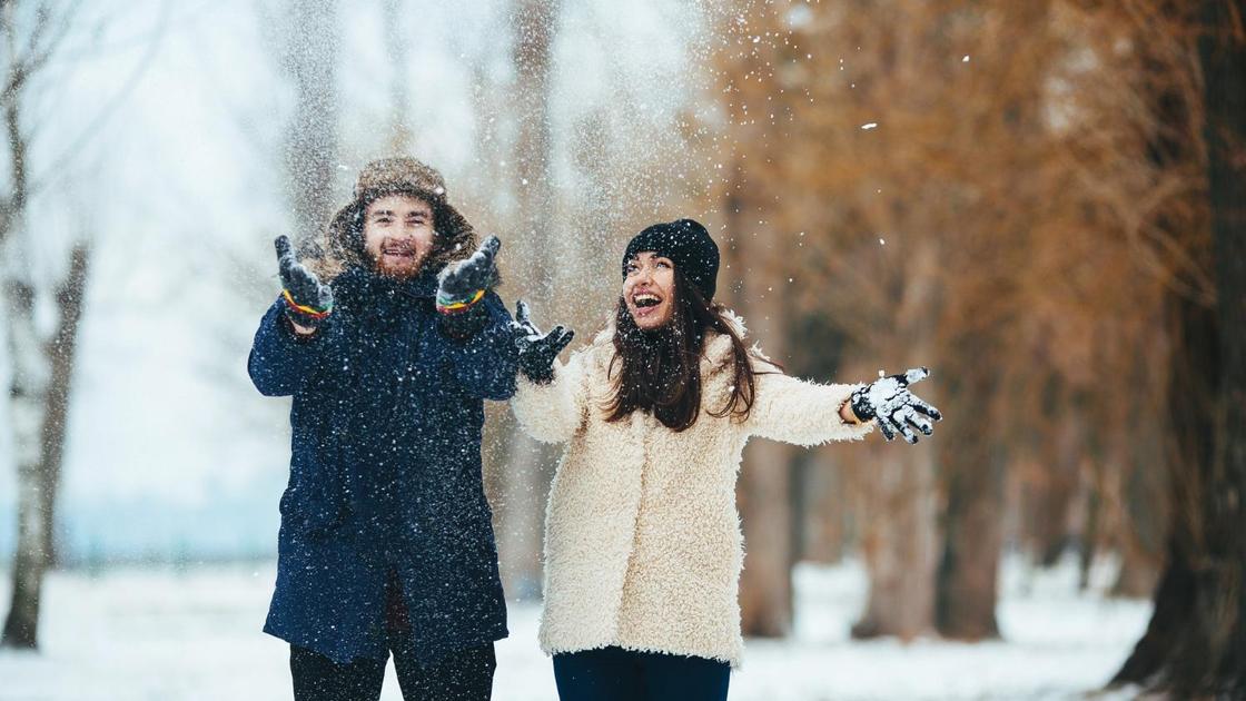 Парень и девушка бросают снег и смеются