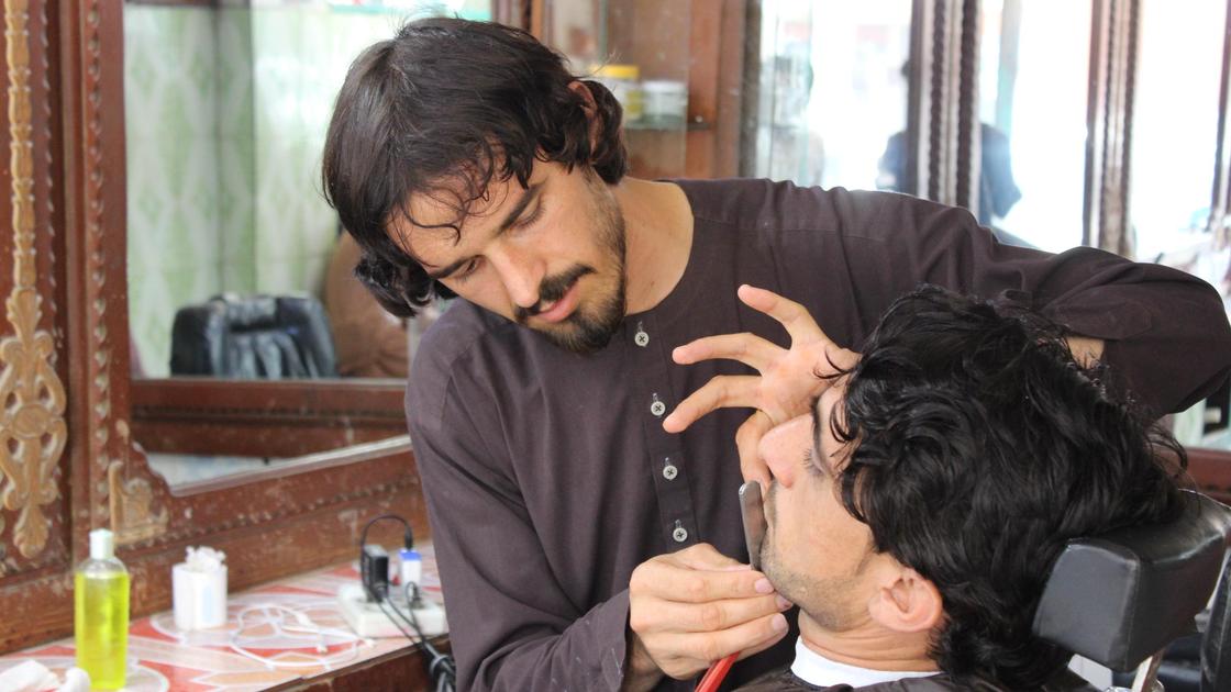 Парикмахер из Афганистана с клиентом