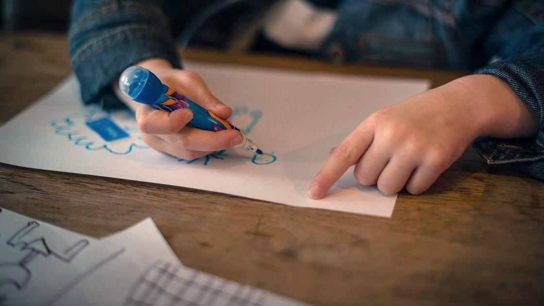 Ребенок что-то рисует на бумаге