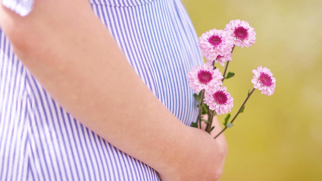 Беременная женщина держит в руках цветы