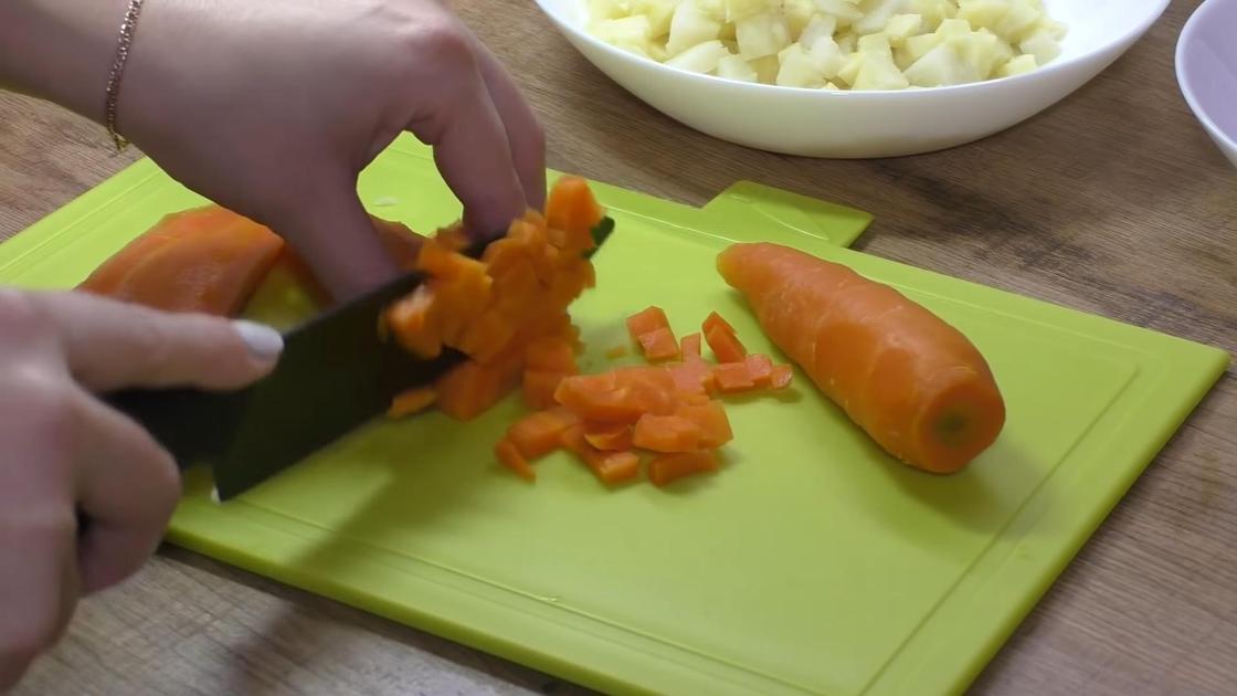 На разделочной доске нарезают отваренную морковь