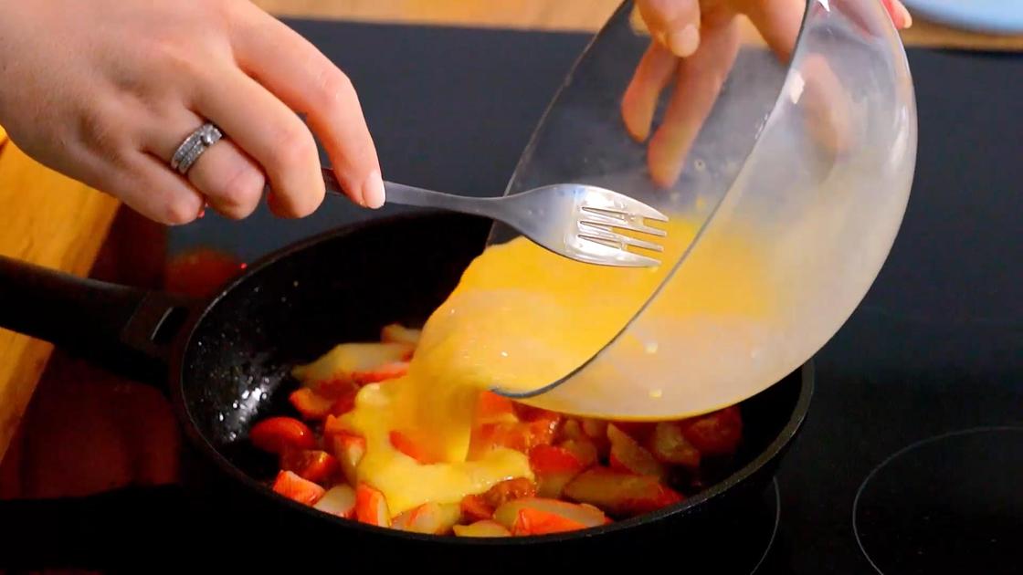 В сковороду с томатами и крабовыми палочками добавляют взбитые яйца