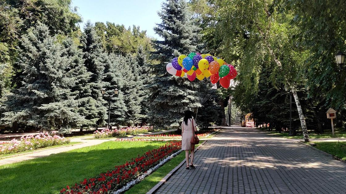 Девушка с шарами идет по парку