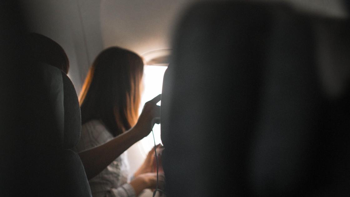 Пассажирка сидит в кресле самолета