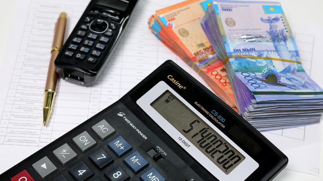 Калькулятор, деньги, телефон и ручка лежат на листах бумаги
