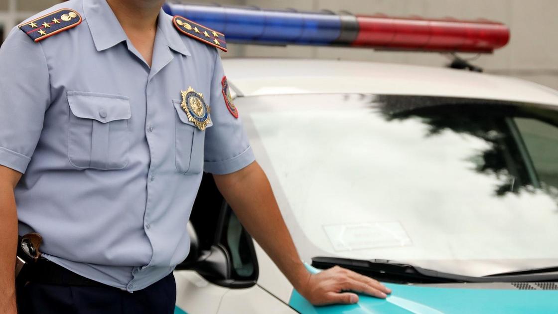 полицейский стоит возле служебной машины