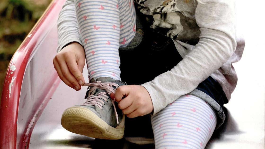Девочка завязывает шнурки