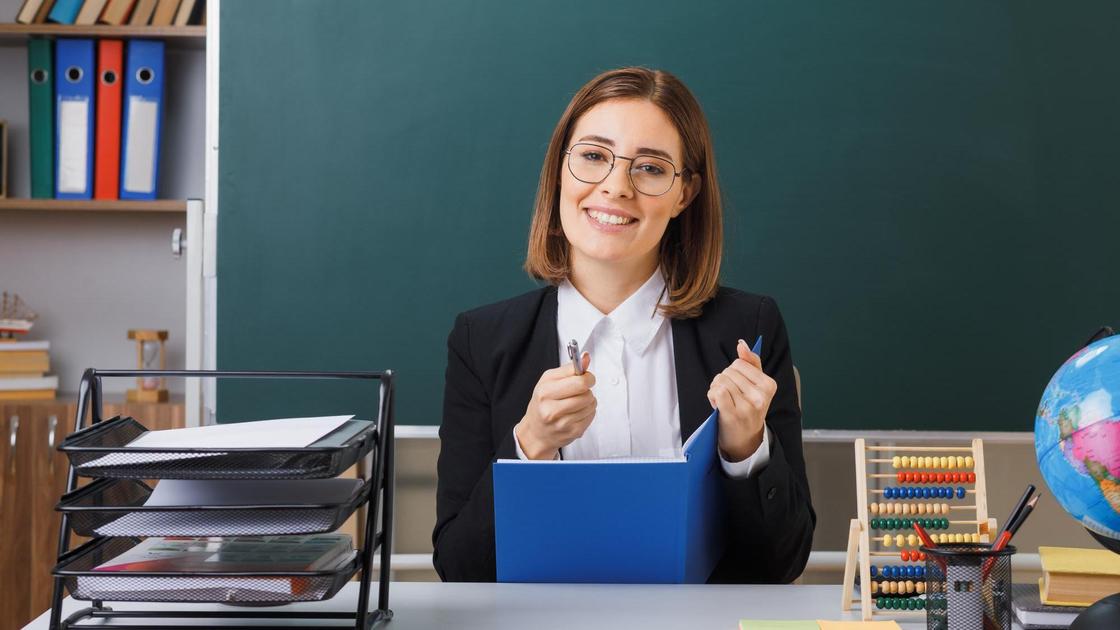 Женщина в очках сидит в школьном классе