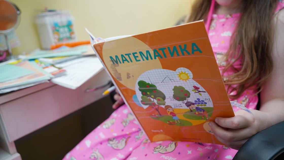 Девочка читает учебник по математике