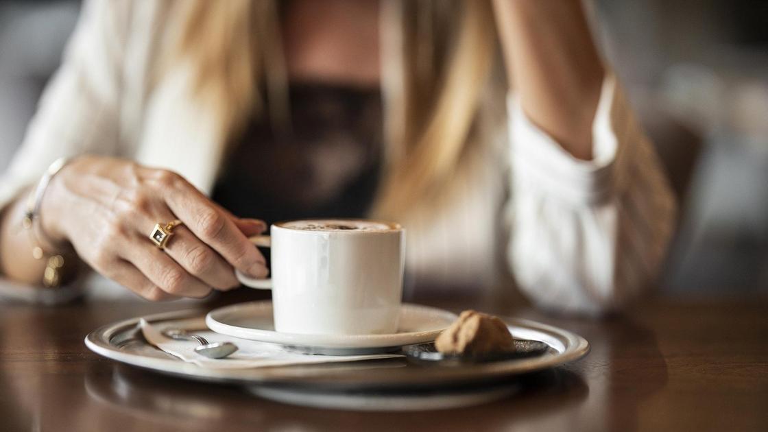 Женщина пьет кофе за столиком