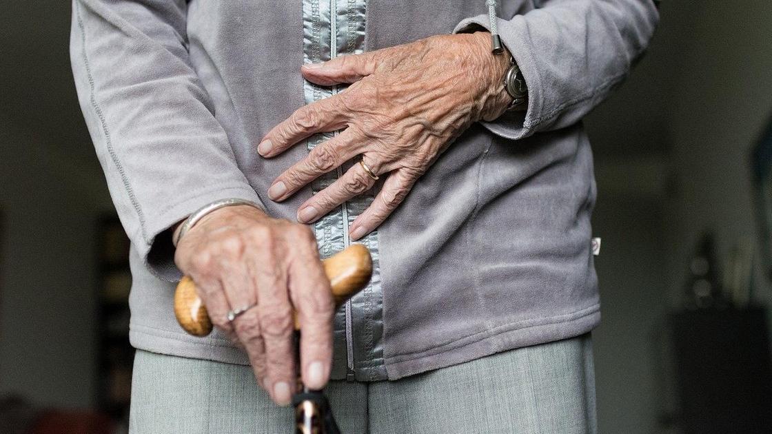 Пожилая женщина держит трость