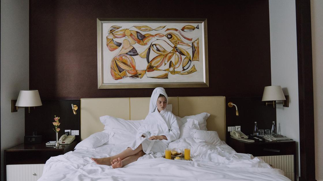 Девушка лежит на кровати в номере отеля