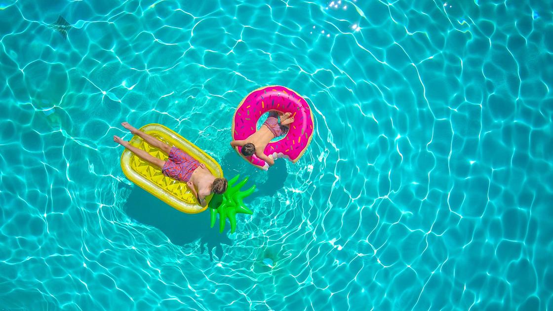 Два человека на надувных кругах плавают в бассейне
