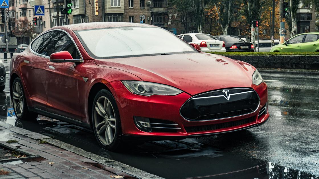 Красная Tesla стоит на обочине дороги